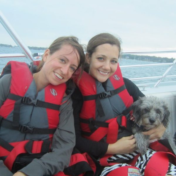 a group of people posing for a picture with a dog on a boat